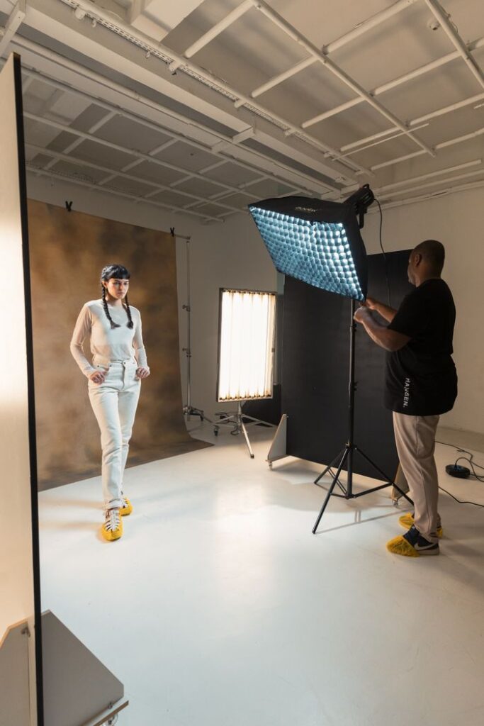 Photographer working with a model in a well-lit indoor studio setting.